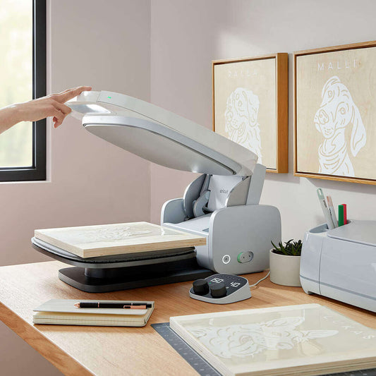 Cricut-Maschine auf einem Tisch mit Holzplatten und Zeichnungen, ideal für kreatives Arbeiten.